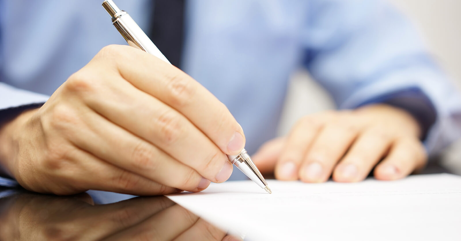 Mans hand holding a pen signing a legal document 